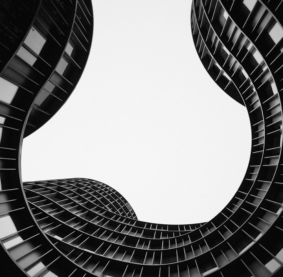 The interior curve of a building seen from the ground looking up.